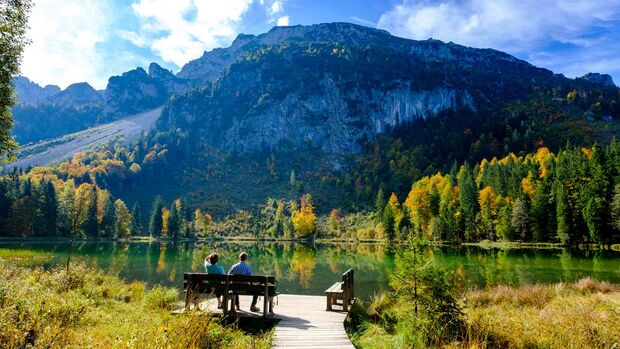 Deutschland, Bayern, Oberbayern, Chiemgau, Inzell, Frillensee: Wanderer sitzen auf Bank im Herbst