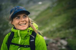 Frau in Wanderkleidung mit Cap in bergiger Landschaft