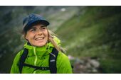 Frau in Wanderkleidung mit Cap in bergiger Landschaft