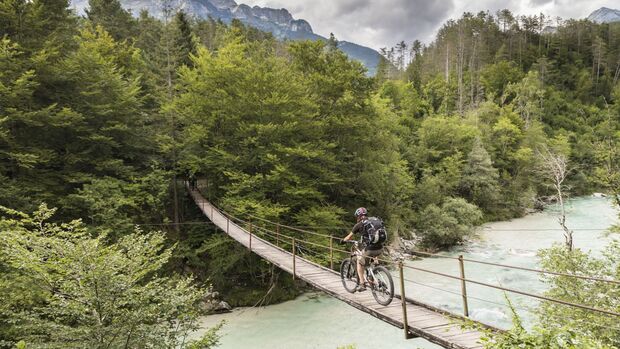 Male mountainbiker is crossing a suspension bridge in Slovenia.
