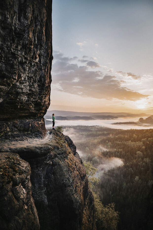 Side View Of Woman Standing On Rock Against Sky During Sunset