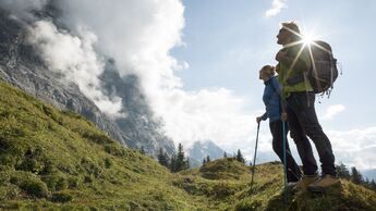 Wanderndes Pärchen hält auf dem Kamm inne, schaut zu den Bergen.