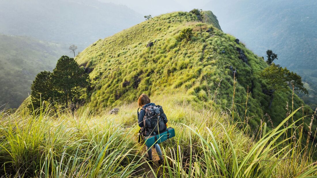 Young woman hikes through hilly jungle terrain
