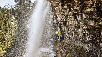 Zwei Personen laufen seitlich an einem Wasserfall vorbei