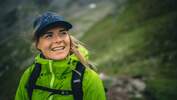 Frau in Wanderkleidung mit Cap in bergiger Landschaft