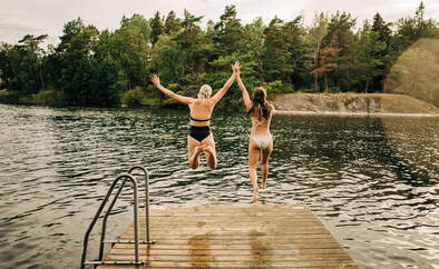 Zwei Frauen springen in den See - Sommerurlaub in Schweden