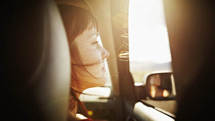 Woman with hair blowing looking out window of car