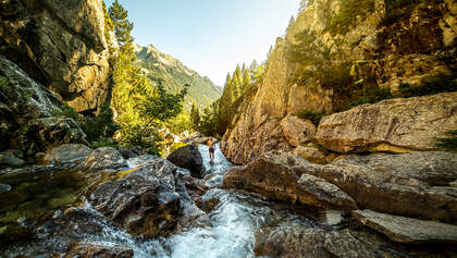 Adventurer standing in stream among mountains