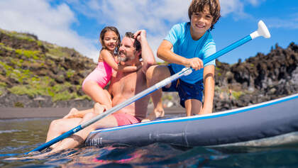 Mann mit Kindern auf SUP im Wasser