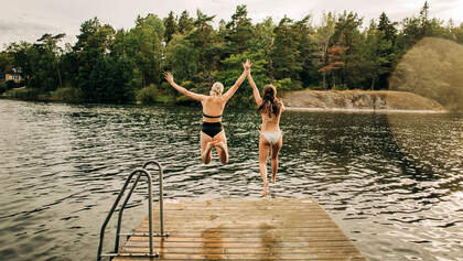 Zwei Frauen springen in den See - Sommerurlaub in Schweden